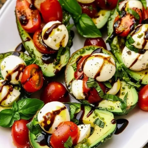 Avocado Caprese Boats with mozzarella and basil served on a plate