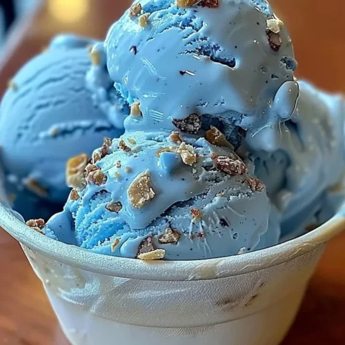 A bowl of Blue Moon Ice Cream topped with a cherry and sprinkles.