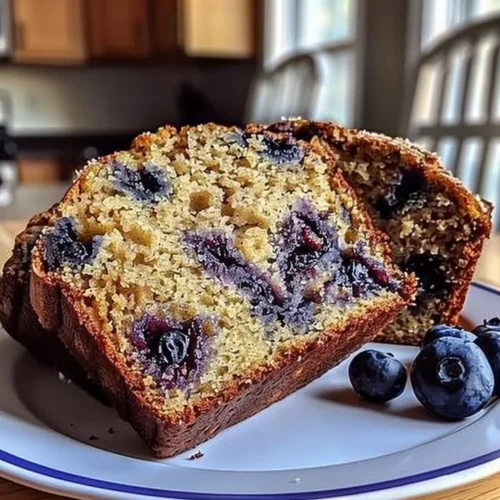 Freshly baked blueberry banana bread slices on a wooden cutting board