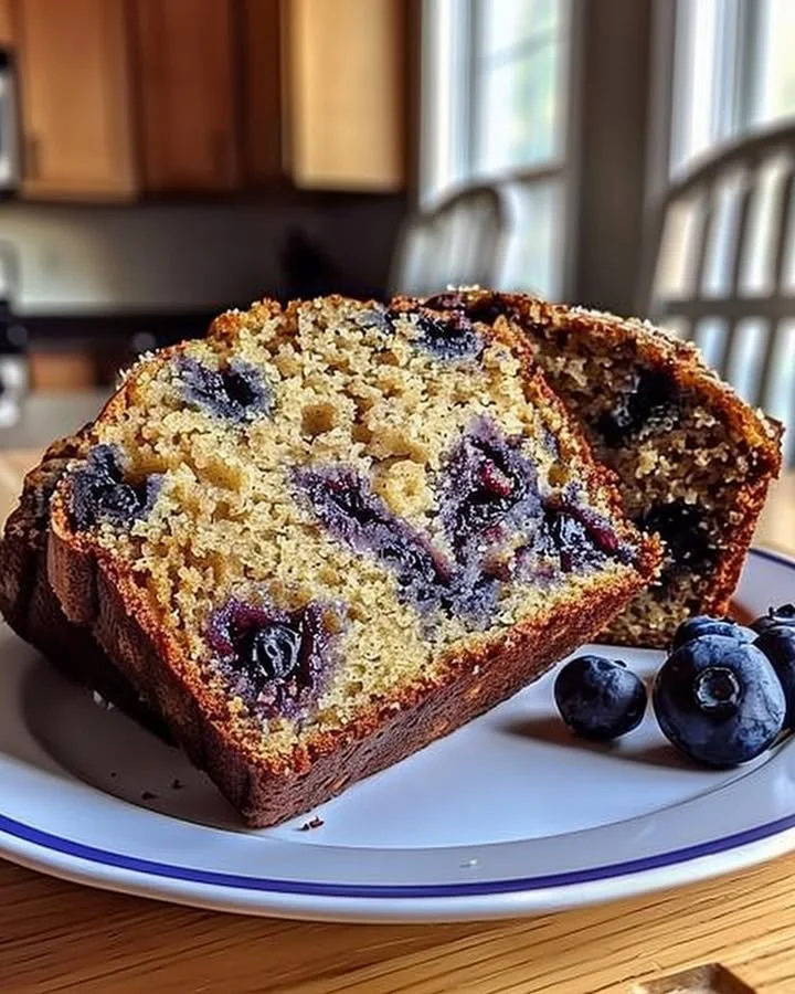 Freshly baked blueberry banana bread slices on a wooden cutting board