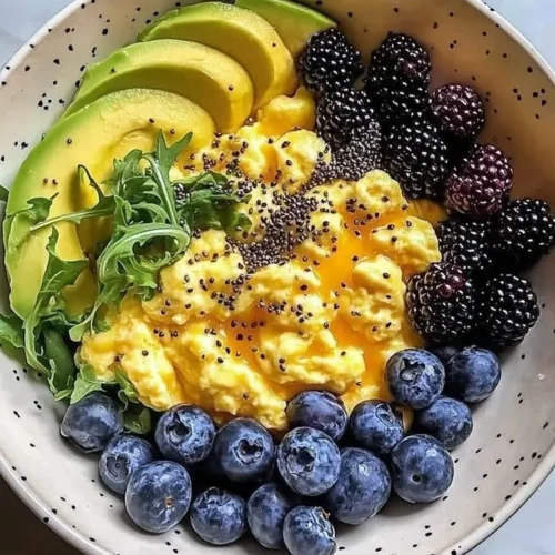 Healthy breakfast bowl with scrambled eggs, avocado, and berries