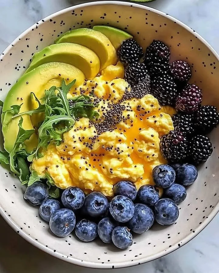 Healthy breakfast bowl with scrambled eggs, avocado, and berries