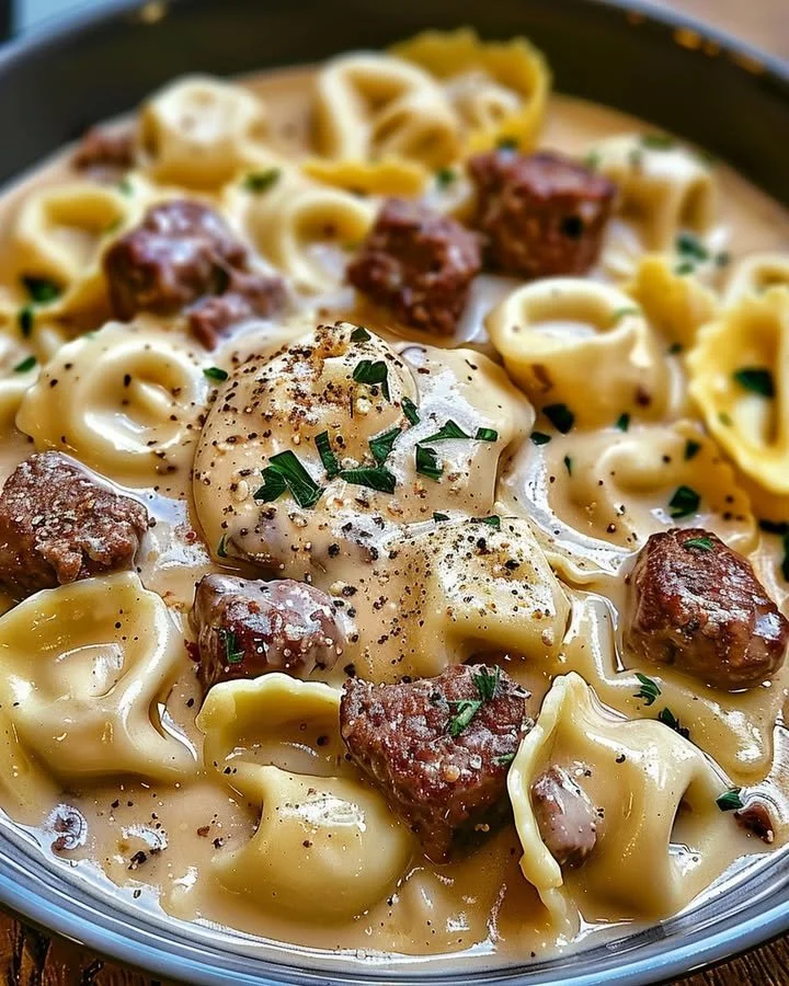 Cheesesteak tortellini in rich provolone sauce garnished with herbs