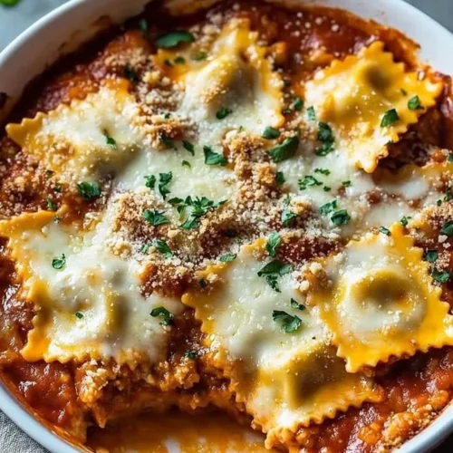 Cheesy baked ravioli casserole served on a plate with herbs