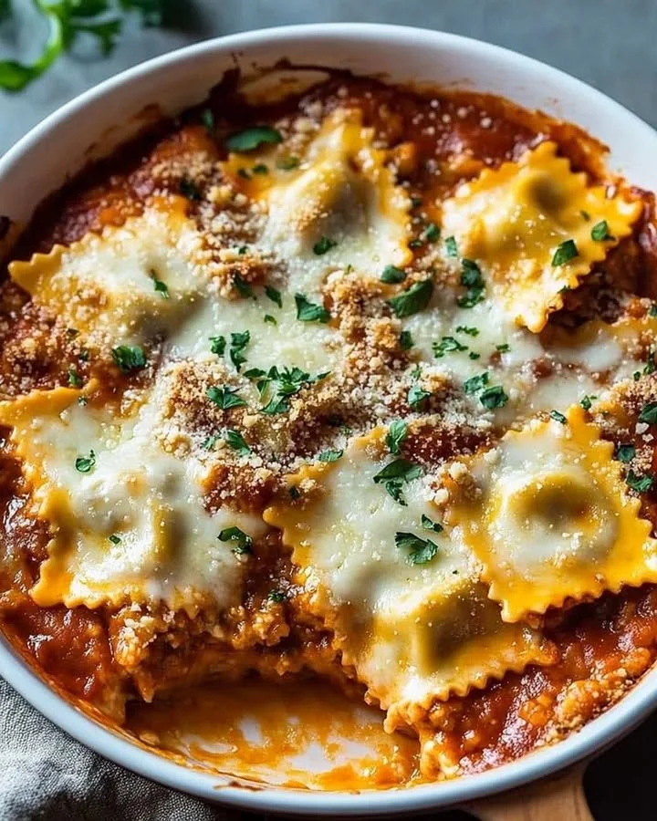 Cheesy baked ravioli casserole served on a plate with herbs