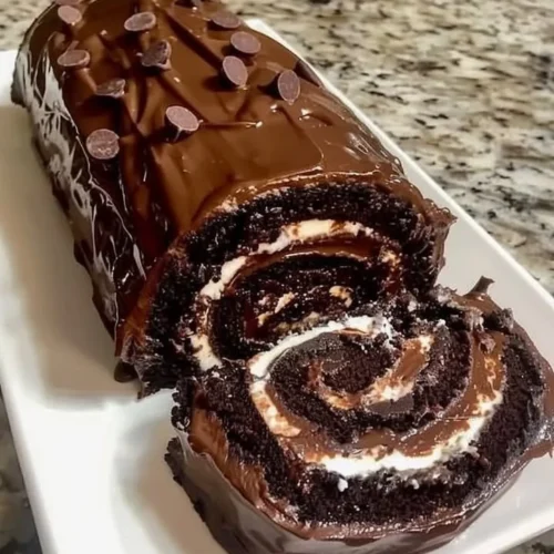 Delicious chocolate cake roll topped with rich chocolate icing and decorative sprinkles.