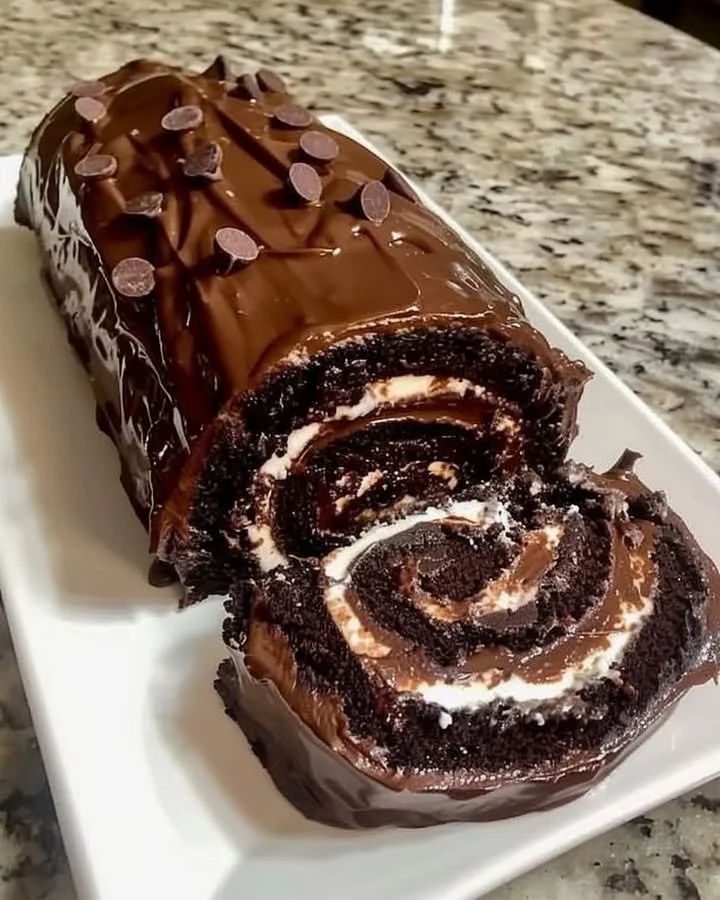 Delicious chocolate cake roll topped with rich chocolate icing and decorative sprinkles.