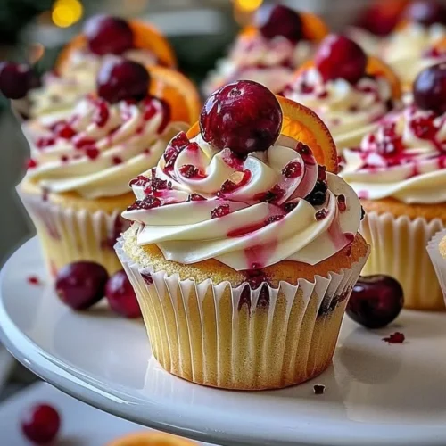 Cranberry Orange Cupcakes with white chocolate frosting on a rustic wooden table.