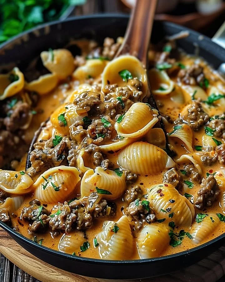 Creamy beef shells casserole topped with cheese and herbs in a baking dish.