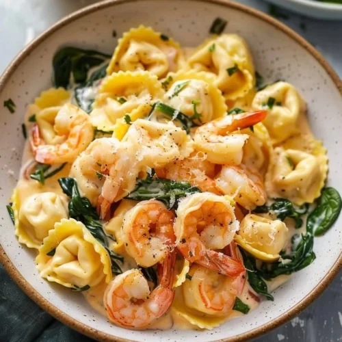 Creamy lemon shrimp tortellini dish garnished with herbs