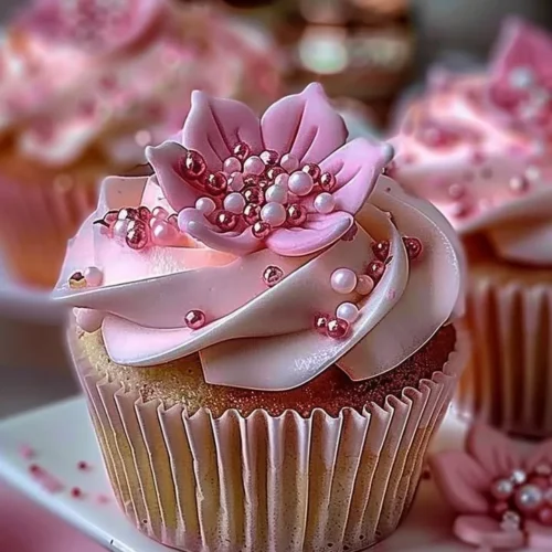 Elegant pink buttercream cupcakes topped with delicate floral designs.