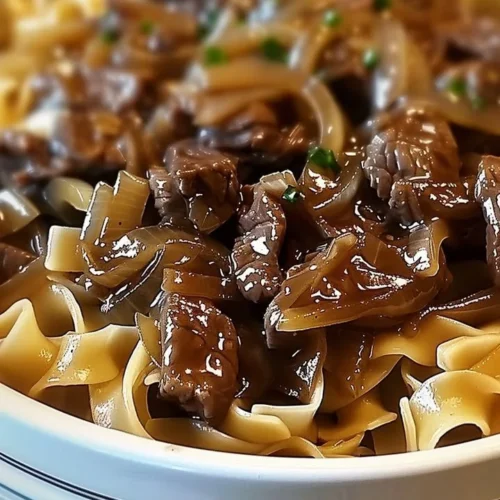 A delicious serving of French onion beef and noodles topped with melted cheese.