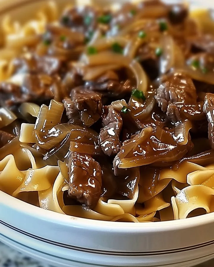 A delicious serving of French onion beef and noodles topped with melted cheese.
