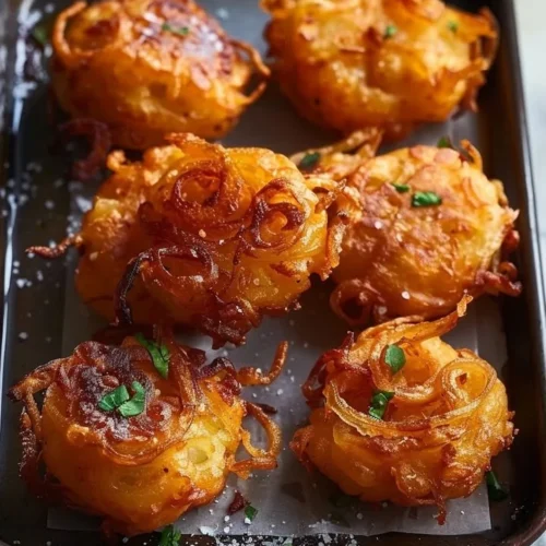 Golden onion fritters served on a plate with dipping sauce