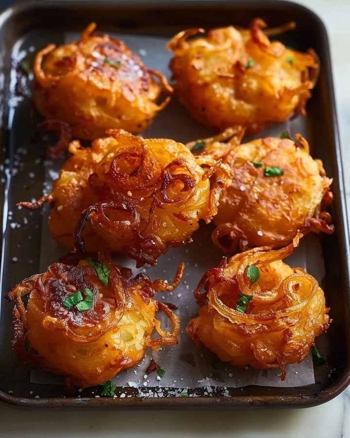 Golden onion fritters served on a plate with dipping sauce