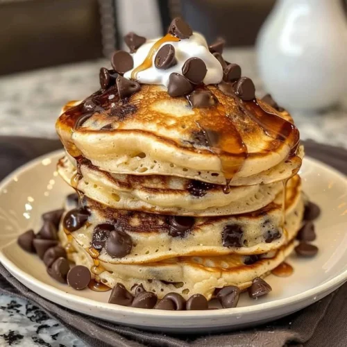 Delicious chocolate pancakes stacked high with chocolate syrup and whipped cream