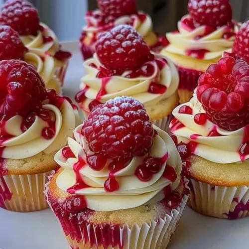 Delicious raspberry cheesecake cupcakes topped with fresh raspberries and cream.