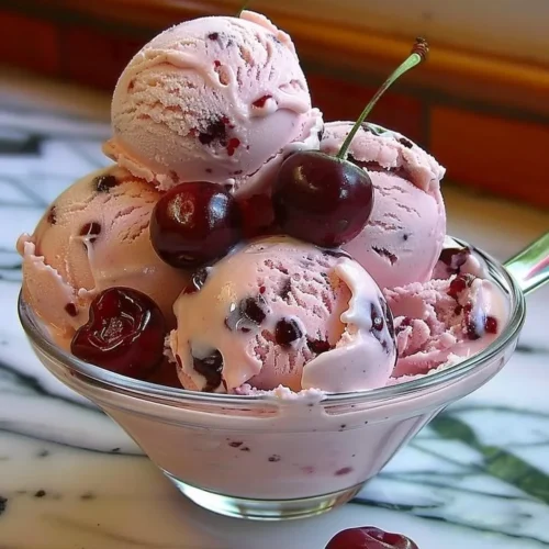 Homemade cherry ice cream in a bowl with fresh cherries on top