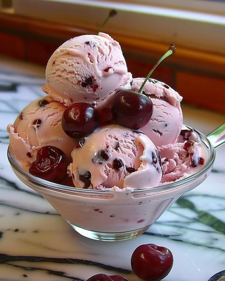 Homemade cherry ice cream in a bowl with fresh cherries on top