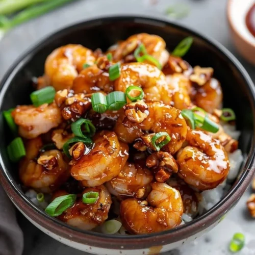 Plate of Honey Walnut Shrimp Delight garnished with walnuts and herbs