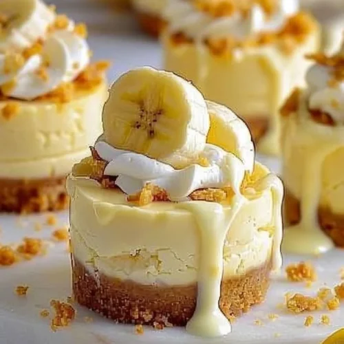 Irresistible mini banana pudding cheesecakes topped with whipped cream and banana slices.