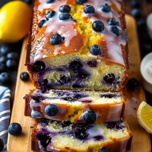 Sliced lemon blueberry yogurt loaf on a wooden cutting board
