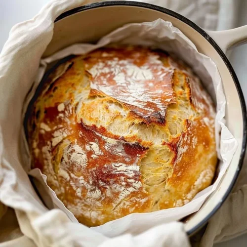 Freshly baked no knead artisan bread loaf on a wooden table.