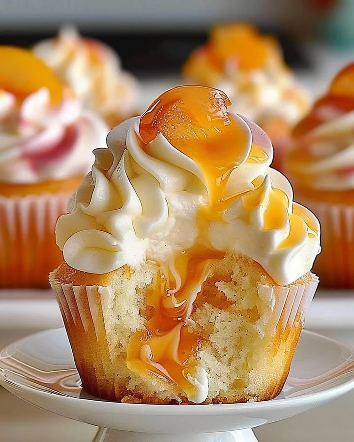 Delicious peach cupcakes with creamy frosting garnished with fresh peaches.