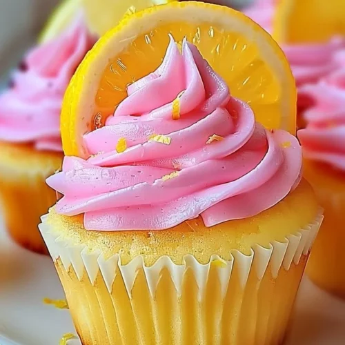 Pink lemonade cupcakes topped with vibrant frosting and garnished with lemon slices.