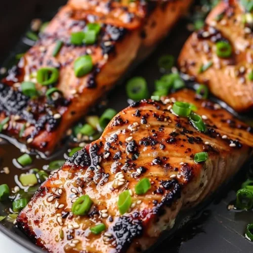 Silken miso-ginger glazed salmon fillet on a plate, garnished with herbs.