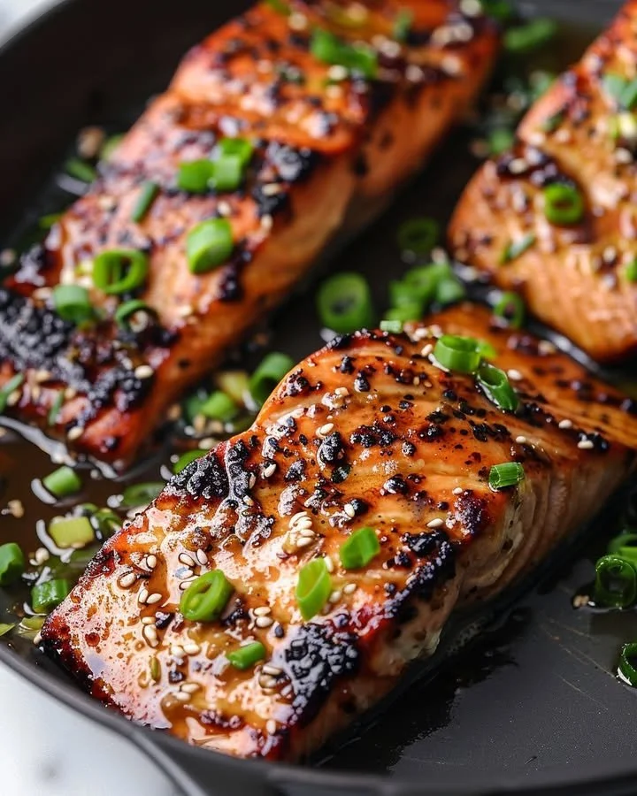 Silken miso-ginger glazed salmon fillet on a plate, garnished with herbs.