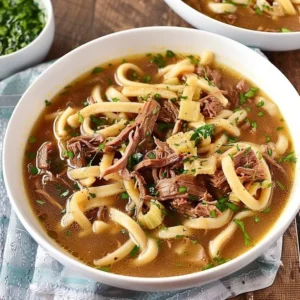 Bowl of slow-cooked beef noodle soup with tender beef and fresh herbs