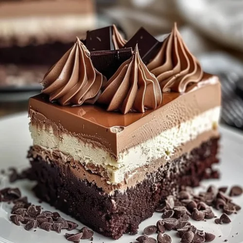 Slice of triple chocolate mousse torte topped with creamy chocolate ganache.