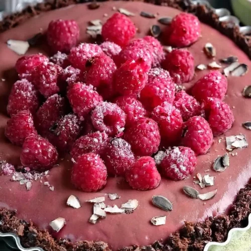 Delicious vegan raspberry chocolate tart topped with fresh raspberries